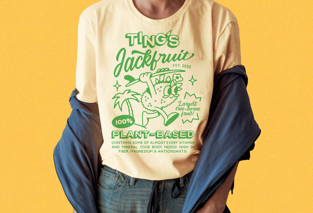 Yellow T-shirt with large graphic of a jackfruit holding a surfboard and font &ldquo;TING&rsquo;S Jackfruit.&rdquo;