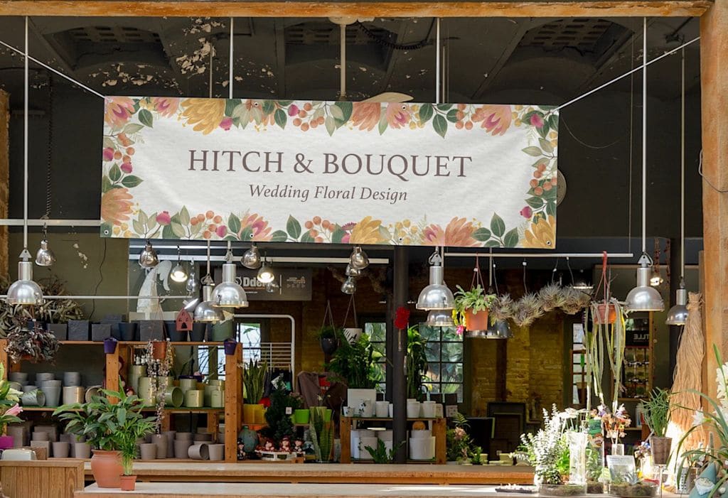 Fabric banner hanging up above a flower shop advertising floral wedding design