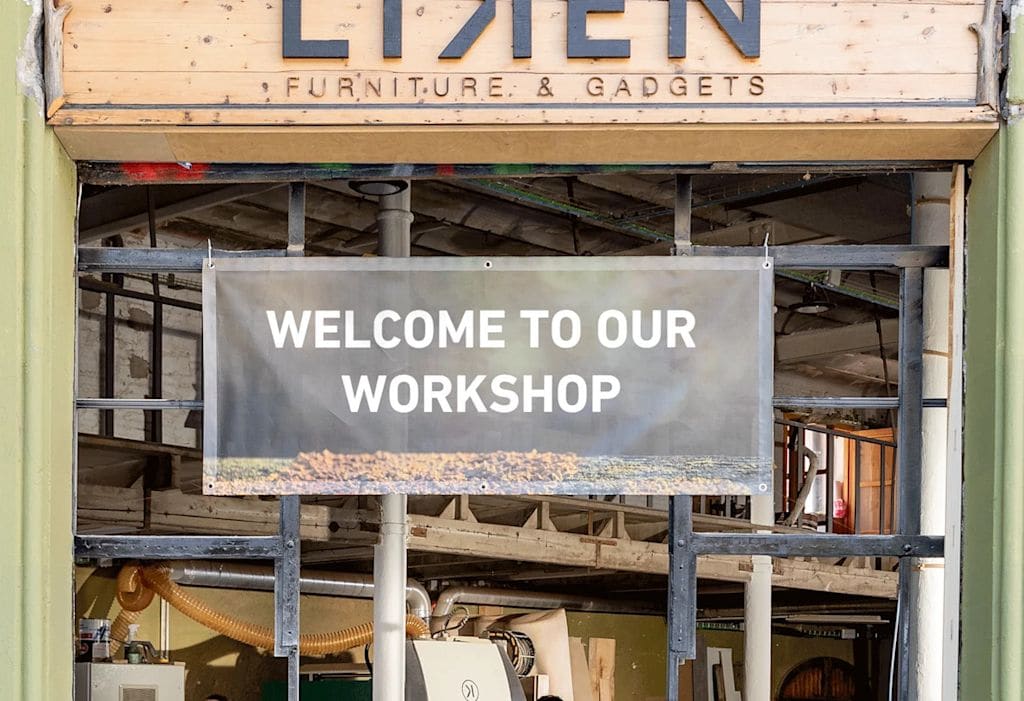 Rectangular mesh banner with text saying &ldquo;Welcome to our workshop&rdquo; hung on a frame