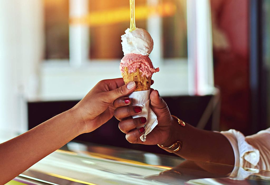 Two hands reaching for an ice cream cone