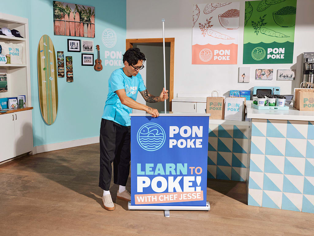 An employee setting up a retractable banner as a part of the storefront design.