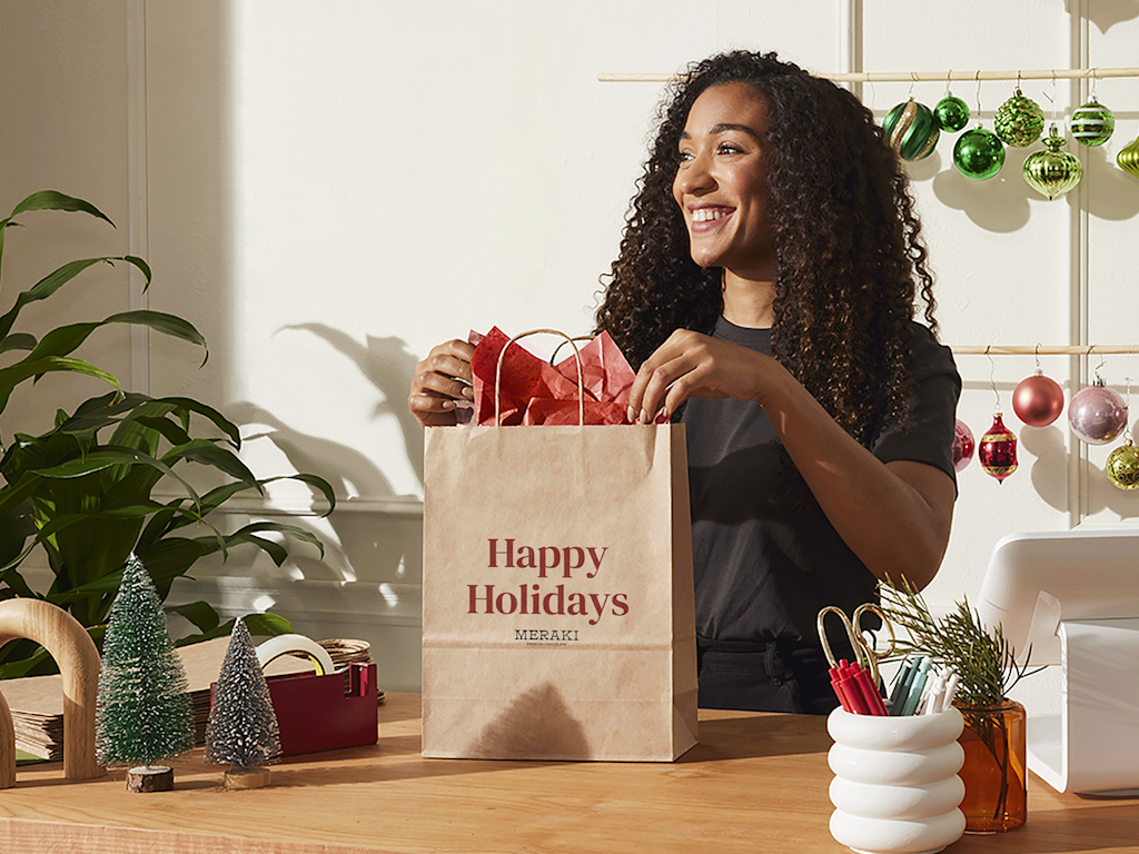 Woman next to a paper gift bag with holiday colors