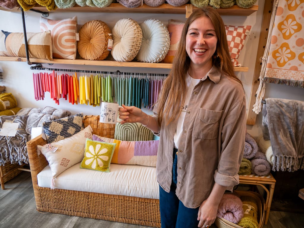 Small business owner of WildFlora standing in her store with a custom mug.