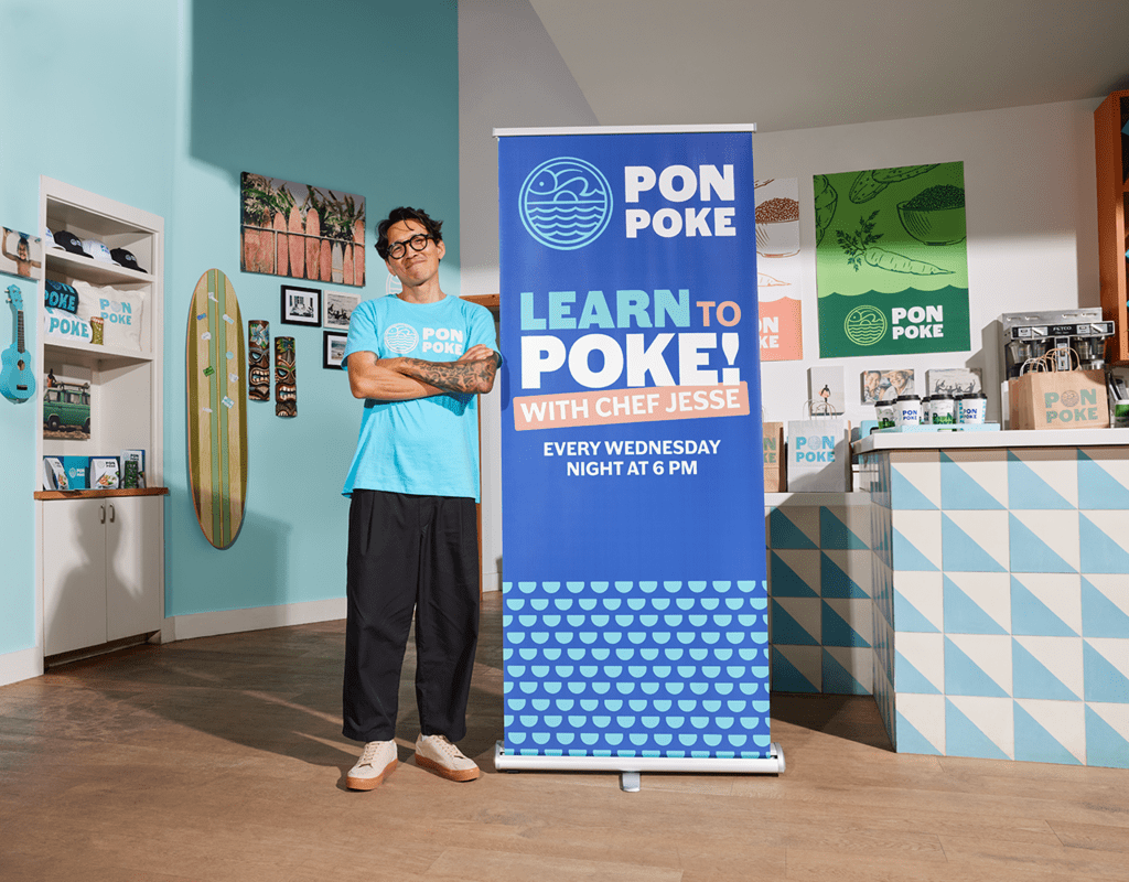 Small business owner standing next to a retractable banner promoting a special event