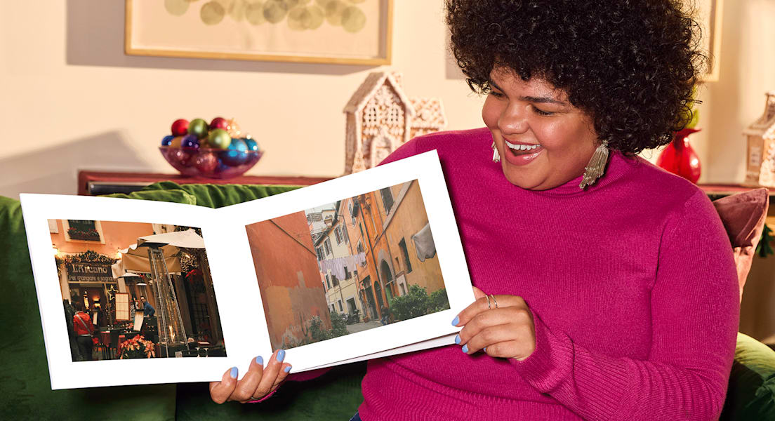 Smiling woman holding her custom photo book, proud of her creation.
