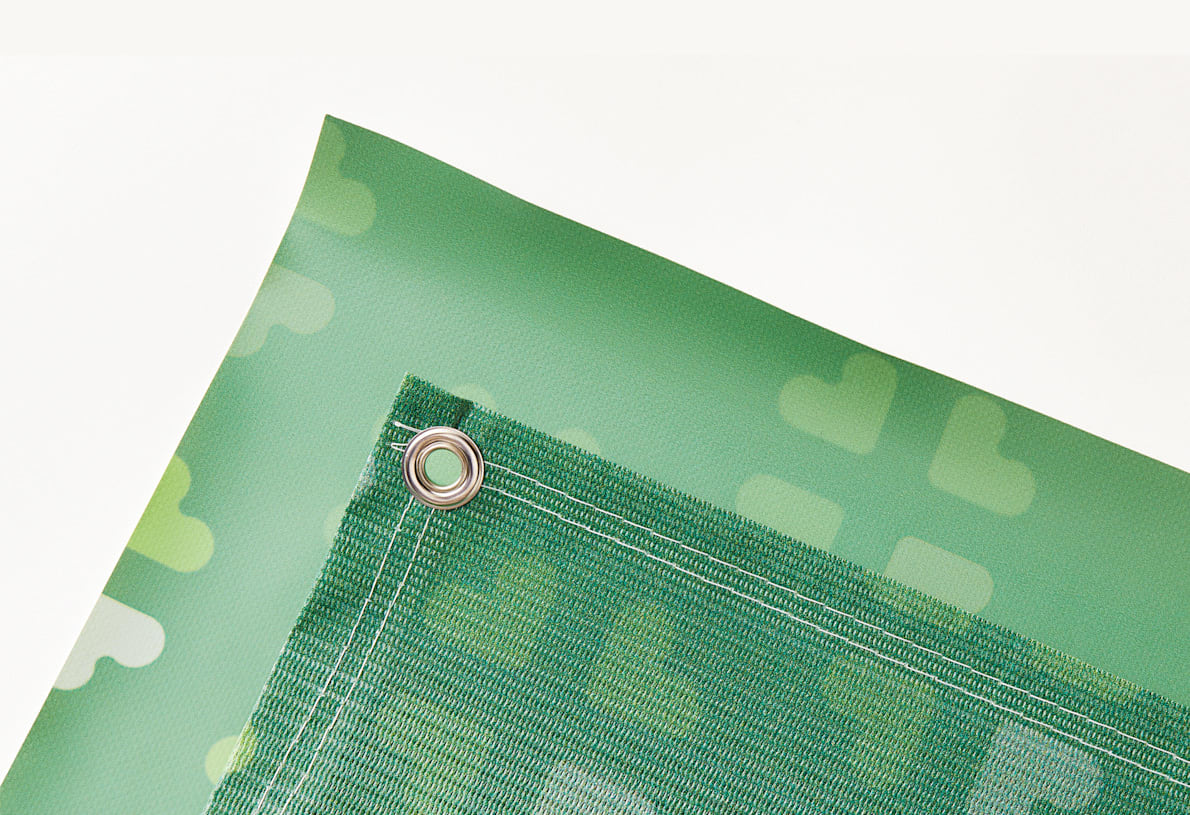 Coin d&rsquo;une b&acirc;che micro perfor&eacute;e verte et son &oelig;illet.