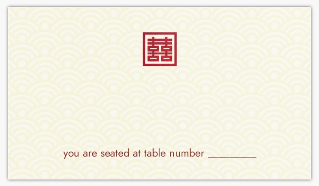 place card featuring a tan fan-like design background and red monogram