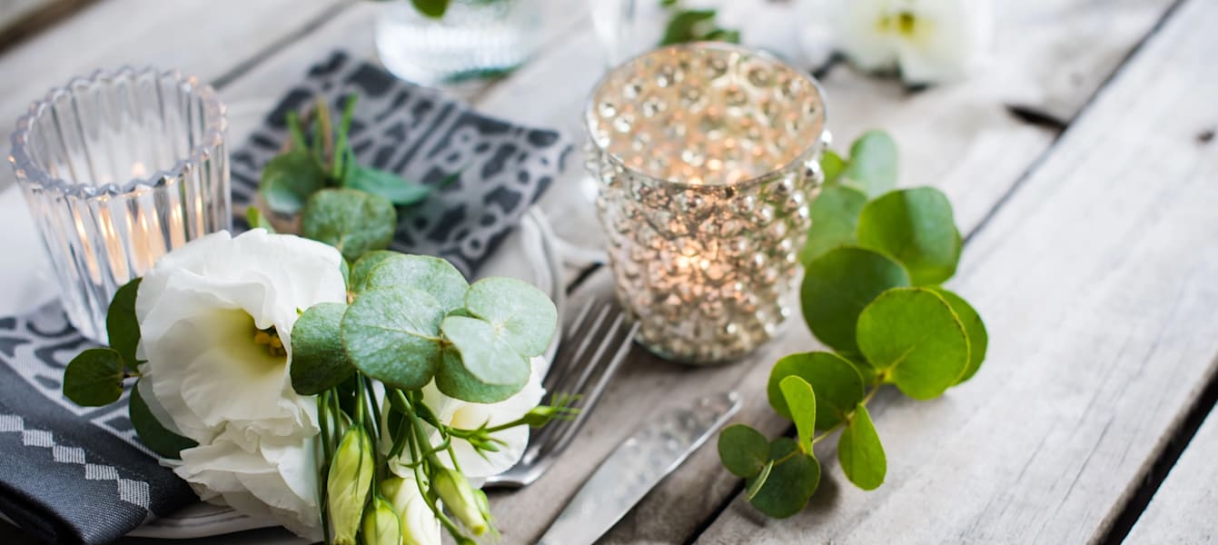 Table decor with white flowers, candles and glasses on old vintage rustic wooden table. Vintage summer wedding table decoration.