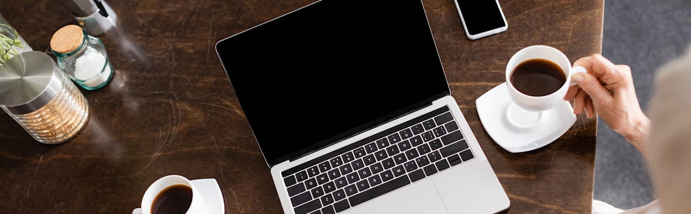 Above images of an open but dark screened laptop, on a desk beside a cup of coffee.