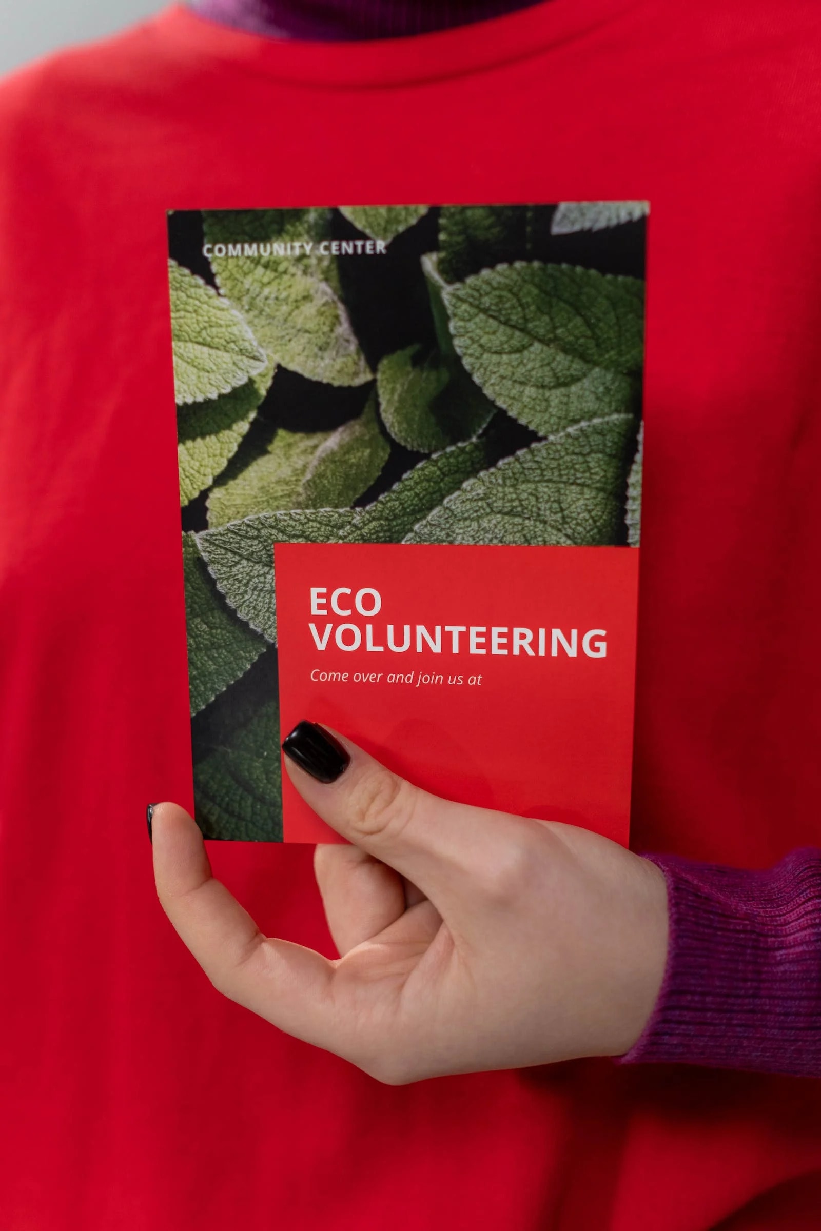 A person holding a red eco-volunteering brochure