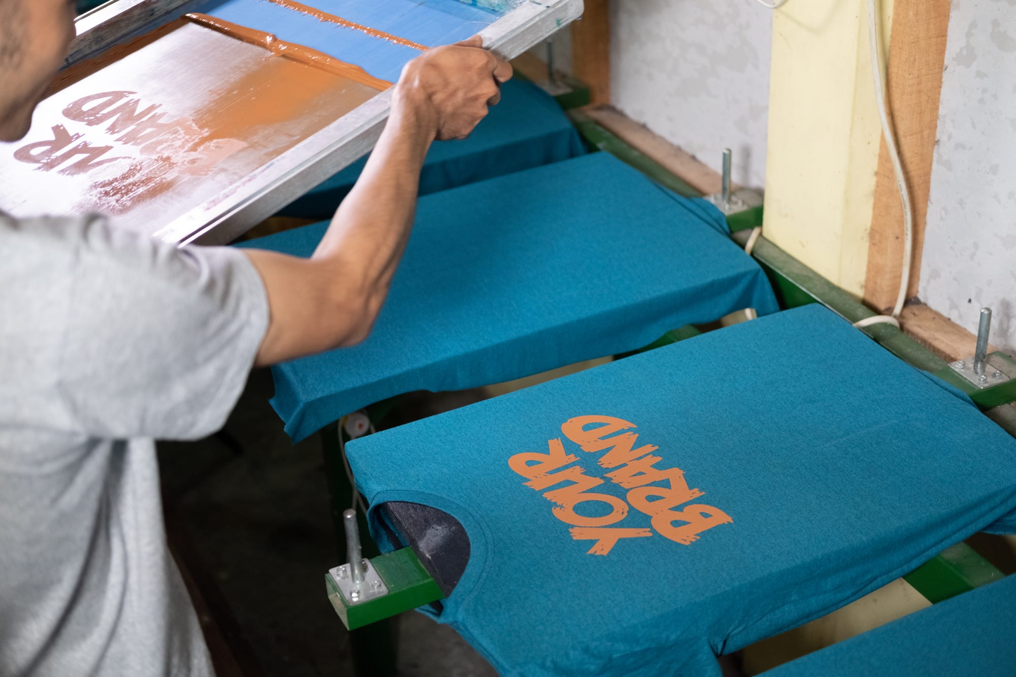 T-shirt printer placing orange designs on blue shirts