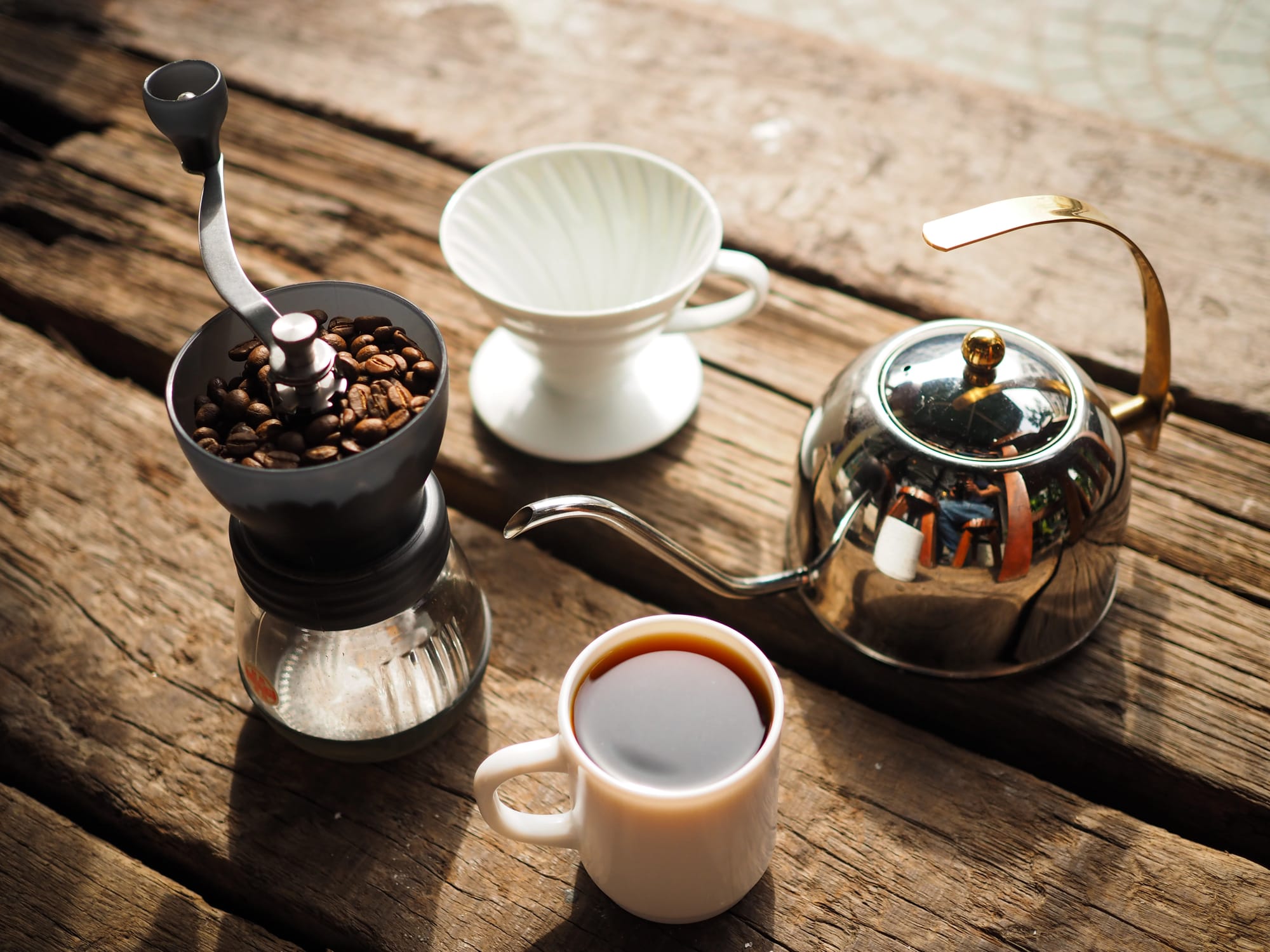 An assortment of coffee products, like a grinder, V60, pot and cup of coffee.