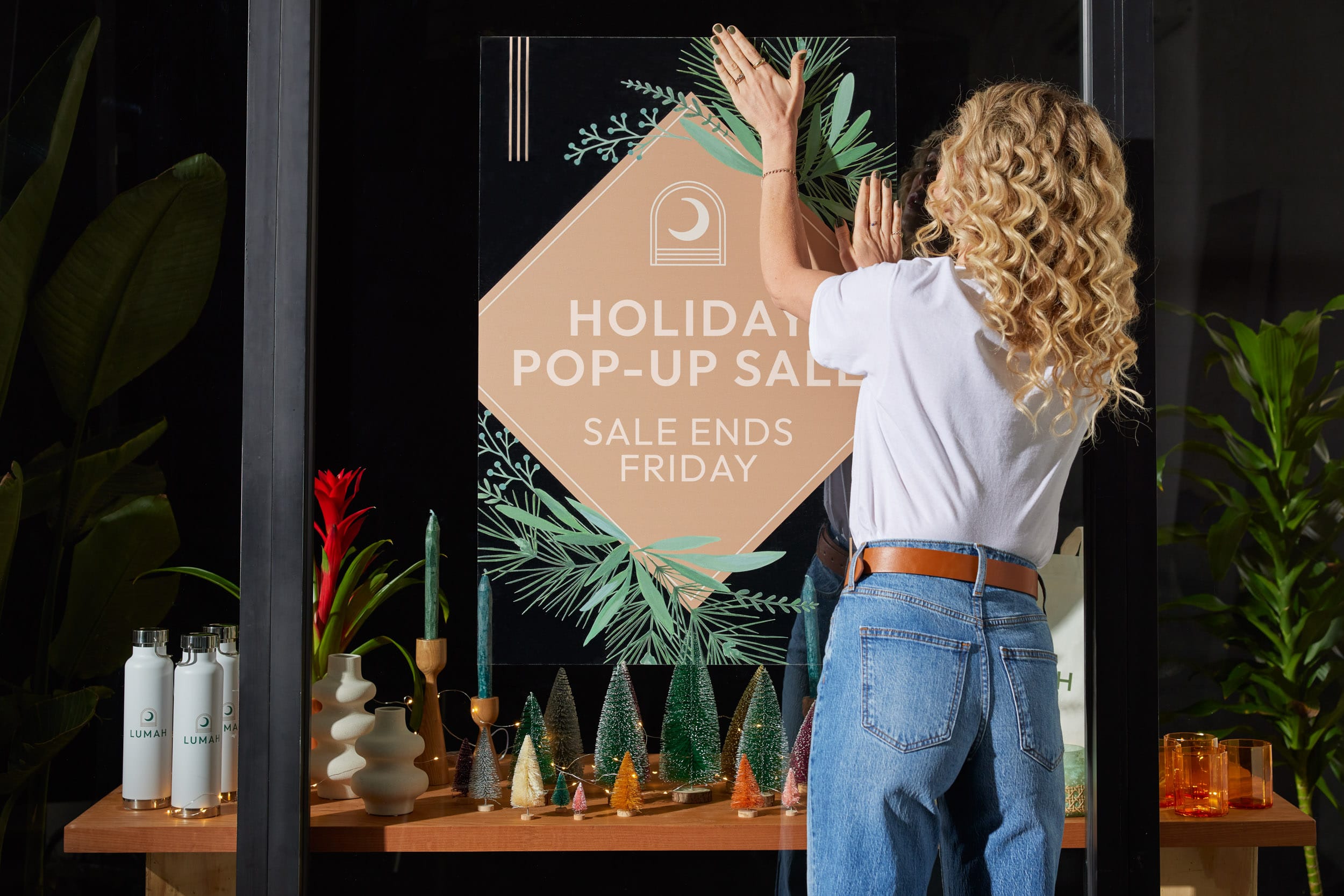 A person hanging up a sign with holiday decoration