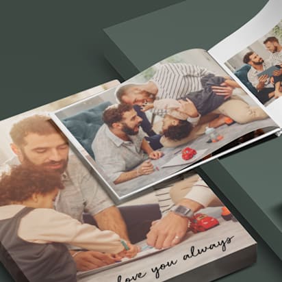 Two photo books featuring images of two dads with their children, next to a mug with a photo of dads printed on it