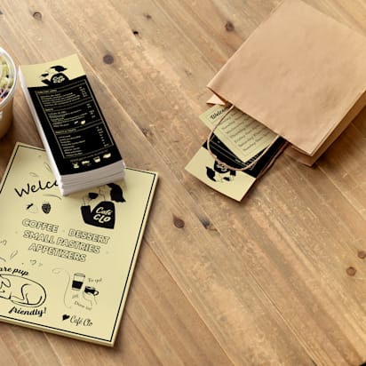 Brown paper bag with branded flyer, brochure and business cards laid out on table