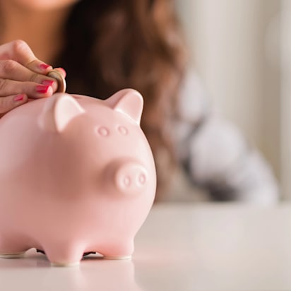 A woman putting a coin into a piggy bank