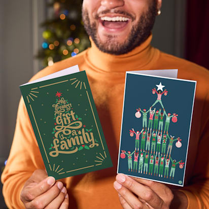 person smiles holding Christmas cards up