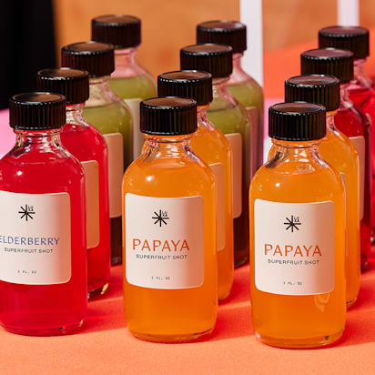 Colorful eco-friendly brand bottles with different superfruit shots labeled papaya, elderberry, and more.