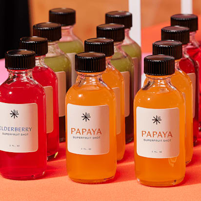 Colorful eco-friendly brand bottles with different superfruit shots labeled papaya, elderberry, and more.