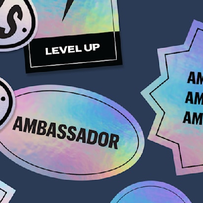 Assorted holographic stickers in different shapes including oval and starburst with ambassador and goals text