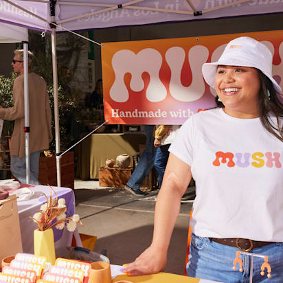 Outdoor event marketing booth at craft fair with branded apparel, signage and promotional display attracting visitors