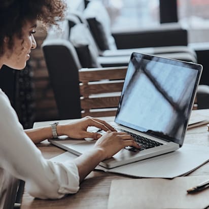 Smiling woman using a laptop at her desk, representing the use of e-commerce tools for business growth.