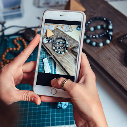 Small business owner photographing handmade bracelets for Instagram marketing.