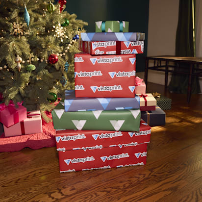 Stacked holiday gift packages with VistaPrint wrapping under a Christmas tree – perfect example of festive branding for small business holiday marketing tips.