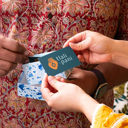 Hands exchanging a branded card and gift box with coordinated colors and logo, representing strong brand presentation