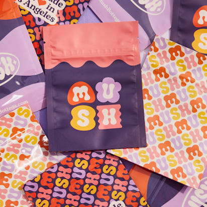 A slection of MUSH branded (logo) items spread out together on a surface eg. notebooks