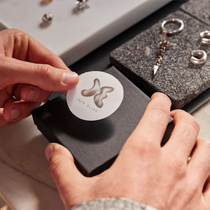 Hand sticks sticker down onto packaging