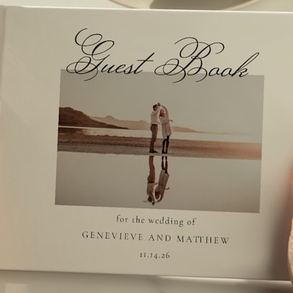 Close-up of a personalized wedding guest book held by a guest, featuring a photo of the couple and elegant script text.