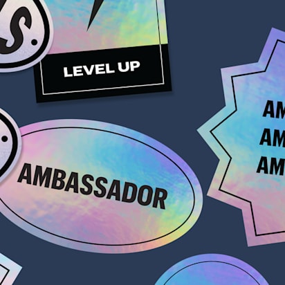 Assorted holographic stickers in different shapes including oval and starburst with ambassador and goals text