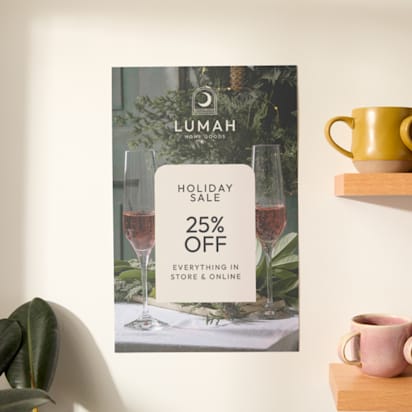 An example of a brand's poster hanging on a wall alongside two shelves filled with mugs. You can see the top leaves of a larger plant coming into the lower frame - presumably the plant is on the floor or another lower surface.