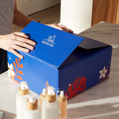 mailer box sizes guide featuring a custom blue branded shipping box being assembled for skincare product packaging