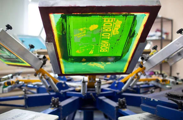 Plastisol print process at clothes factory. Frame, squeegee and plastisol color paints