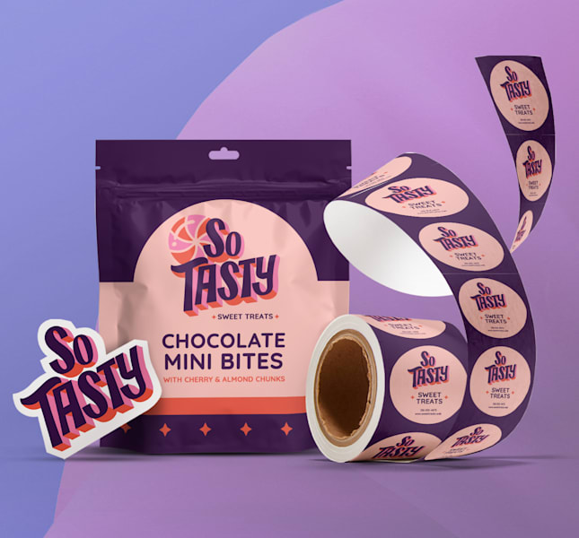 A colourful package of "So Tasty" chocolate mini bites is featured with a background of its brand colours - indigo, purple and a peach pink. The image also features a roll of similarly branded circle stickers, demonstrating VistaPrint product offering.
