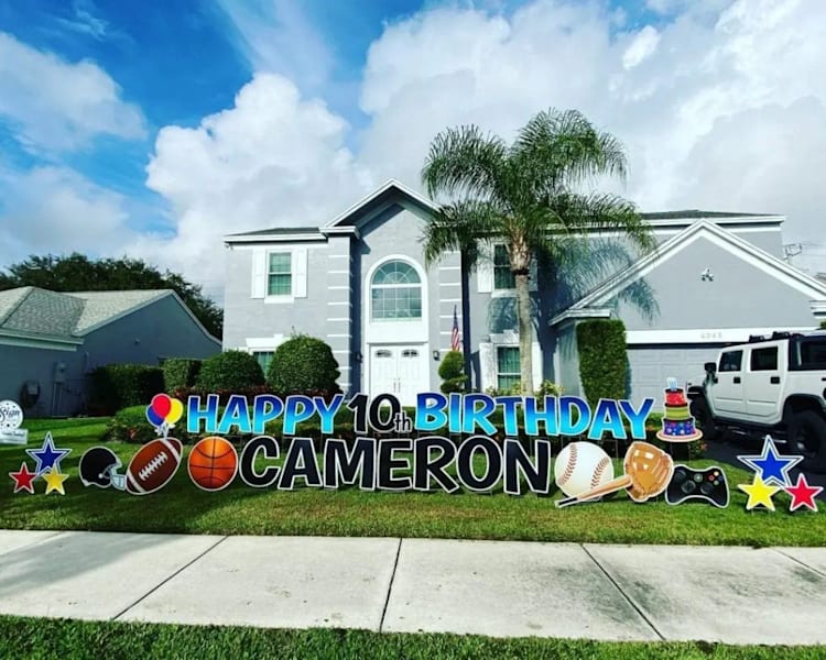 Large birthday yard sign in front of a suburban home spelling out Happy 10th Birthday Cameron with sports-themed graphics