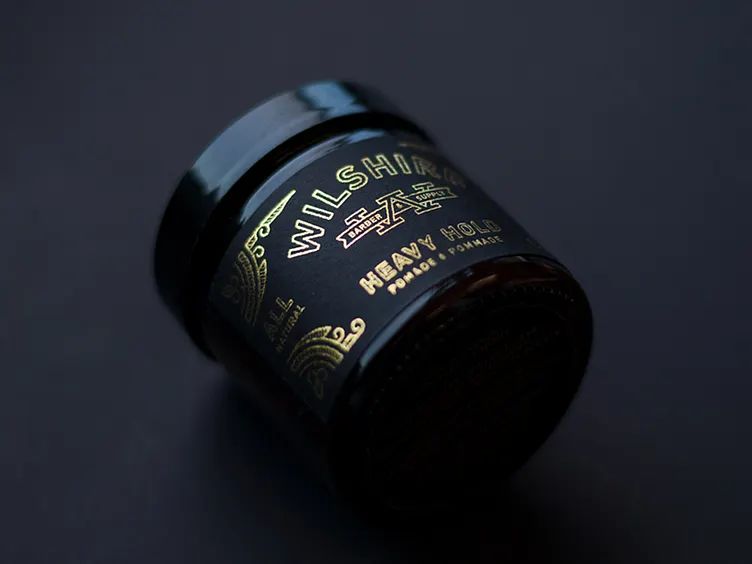 A container of hair pomade using the color trends 2026 Clubroom Contrast black and gold