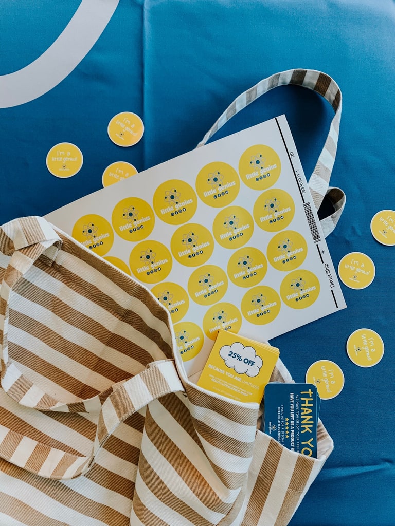 A sheet of round yellow branded stickers with the brand logo and social media icons
