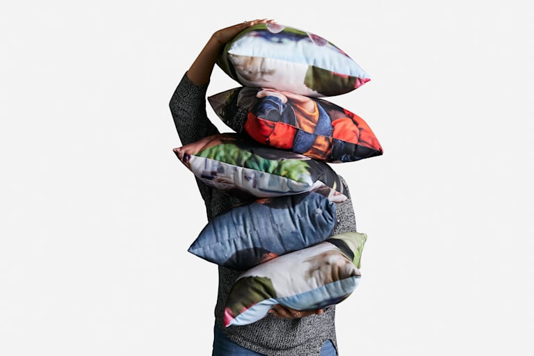 A man holding a stack of cushions
