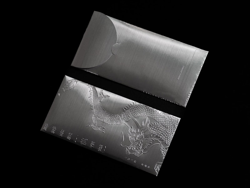 Chrome envelope packaging design with dragon embossing, an example of the Pure Steel packaging trend 2026