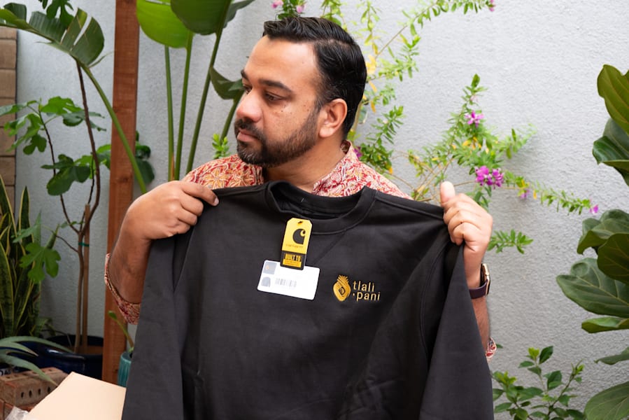 A small business owner holding a branded sweatshirt with an embroidered brand logo