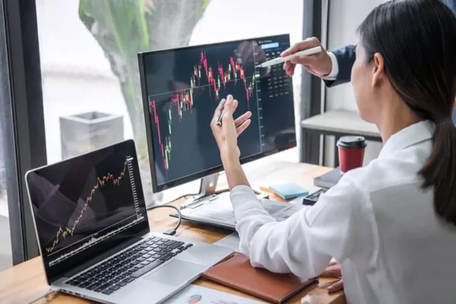 Photo of a woman at a desk looking at monitors