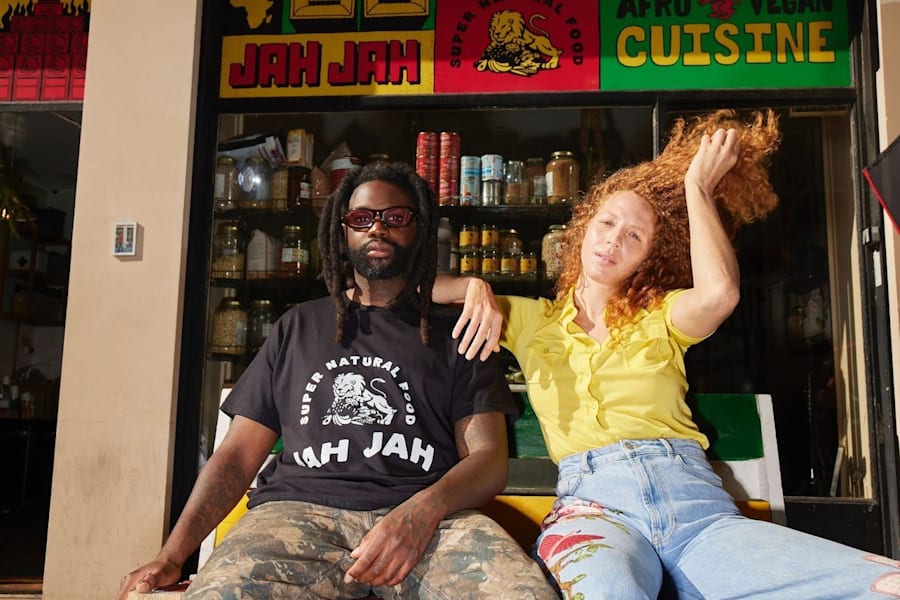Two people outside a restaurant with one wearing a branded T-shirt.