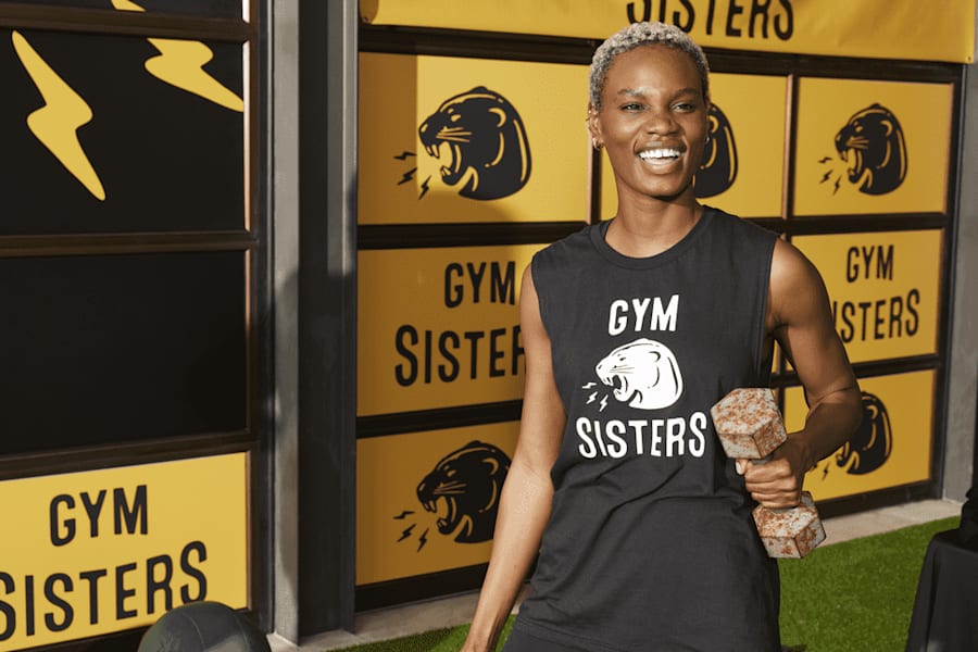 Woman in sleeveless fitness apparel with gym brand logo.