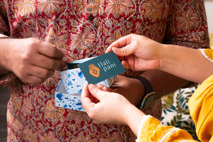 Hands exchanging a branded card and gift box with coordinated colors and logo, representing strong brand presentation