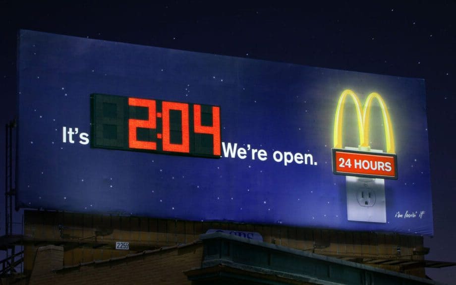 A McDonalds billboard with a digital clock on it.