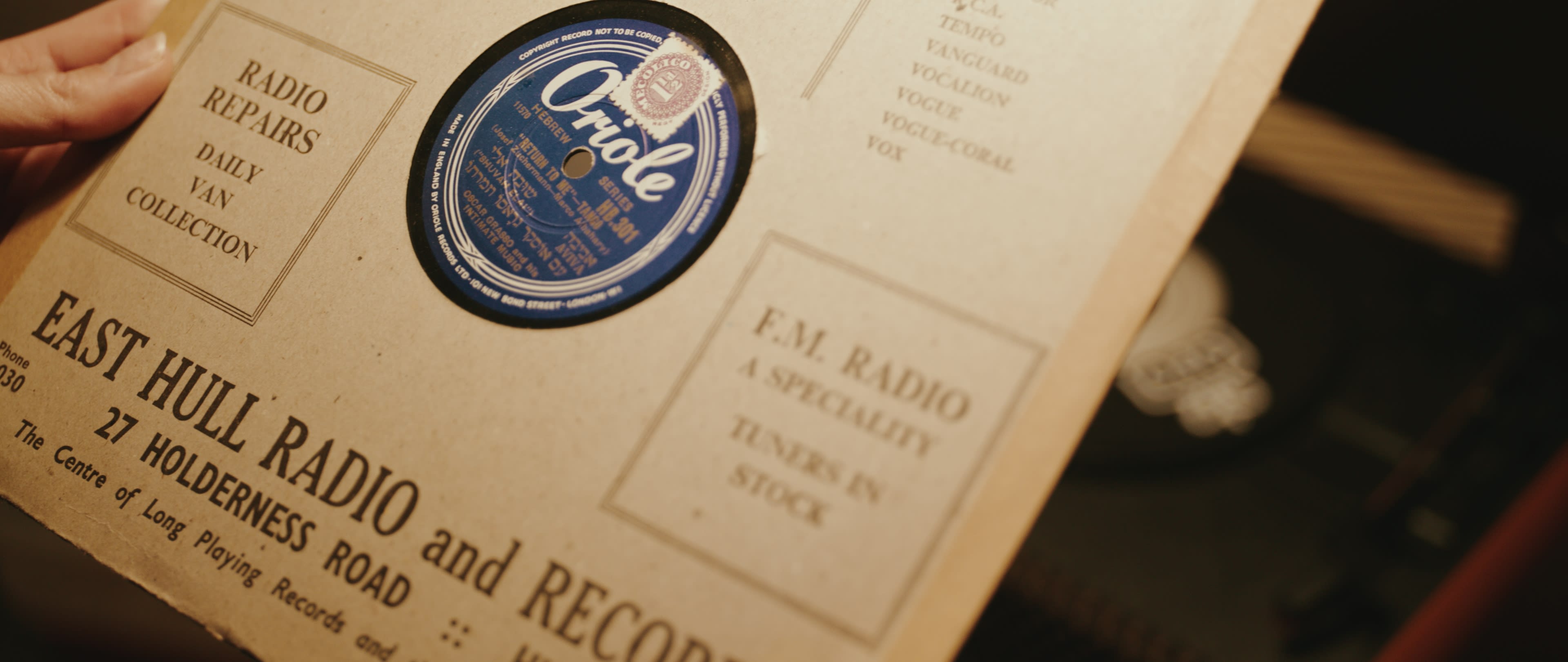 An archival record sleeve held open in a scene from Inheritance