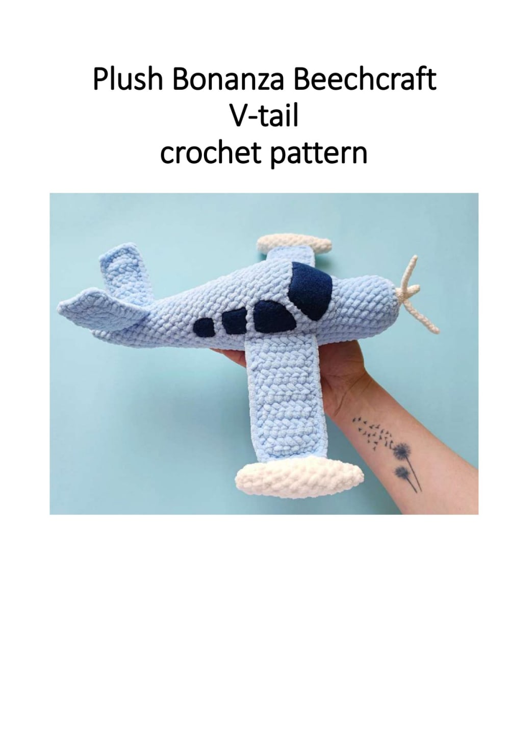Light blue plush crochet airplane with a white propeller and dark blue windows held in a hand
